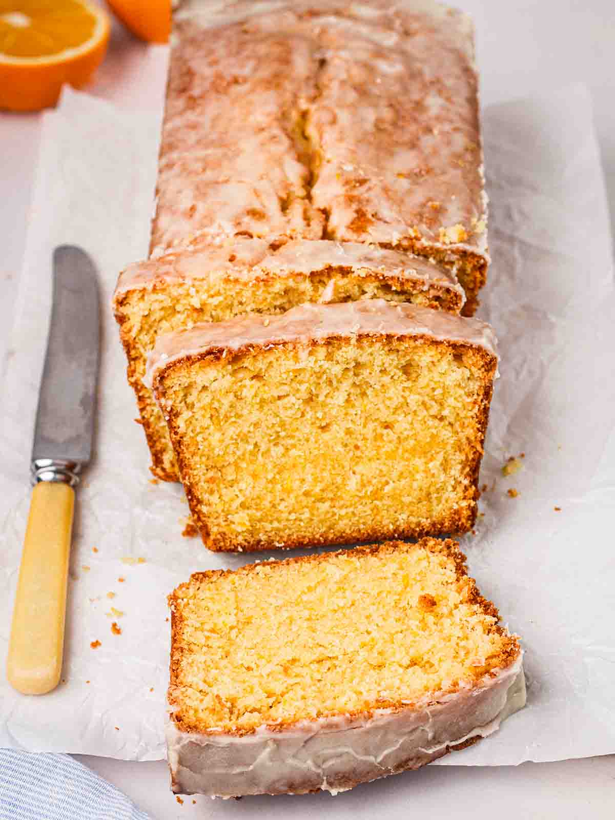 Zesty orange drizzle cake being sliced and ready to eat.