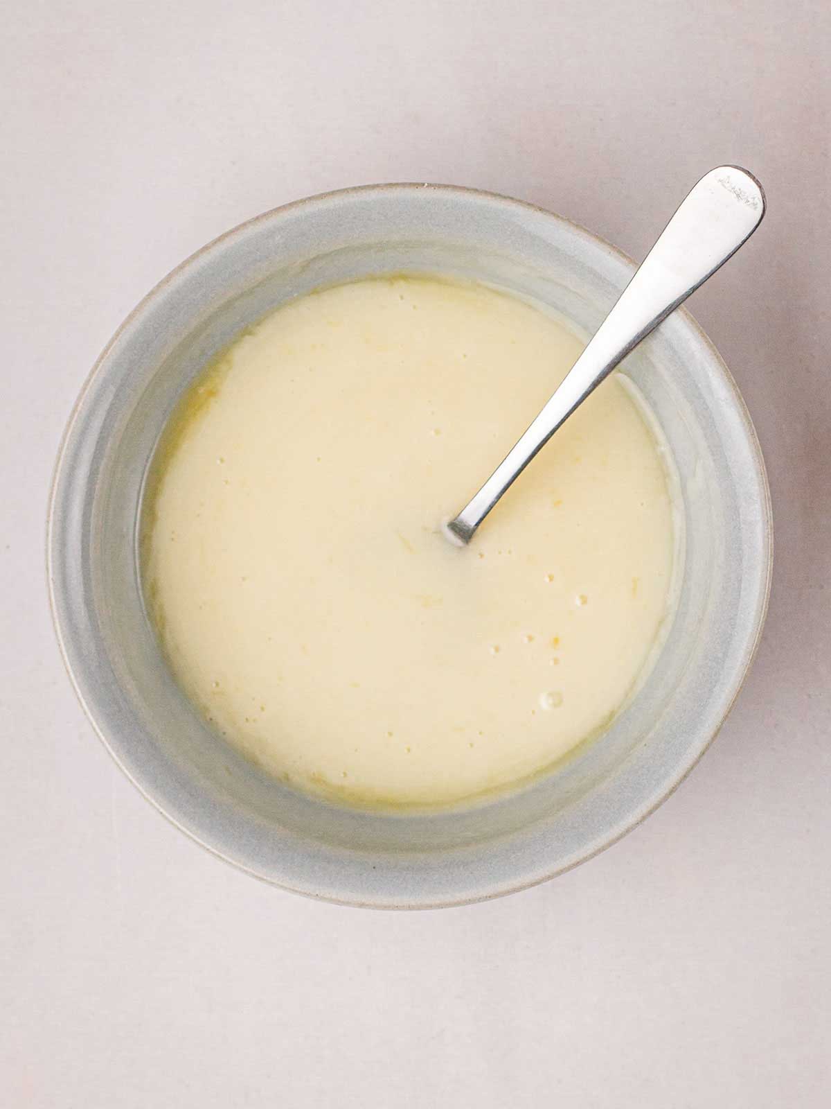 A bowl filled with icing ready to be poured over the Orange Drizzle Cake.