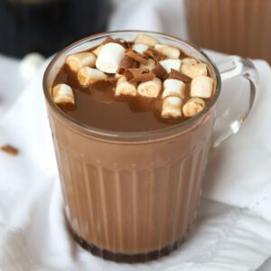 A mug filled with boozy Baileys Hot Chocolate, made in the slow cooker, on a table, topped with marshmallows, ready to eat.