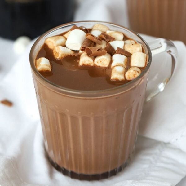 A mug filled with boozy Baileys Hot Chocolate, made in the slow cooker, on a table, topped with marshmallows, ready to eat.