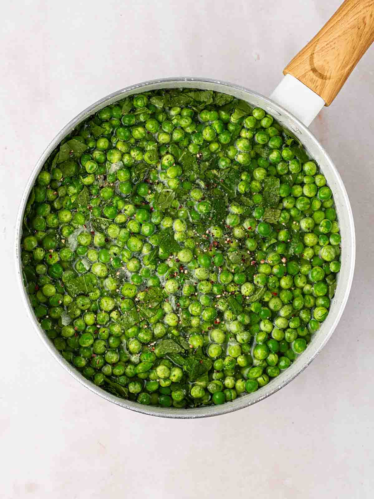Lots of green peas in a pan of water for step 2 in the recipe for Pea and Ham Soup.