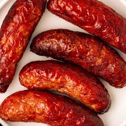 Brown, crispy, cooked sausages on a white plate.
