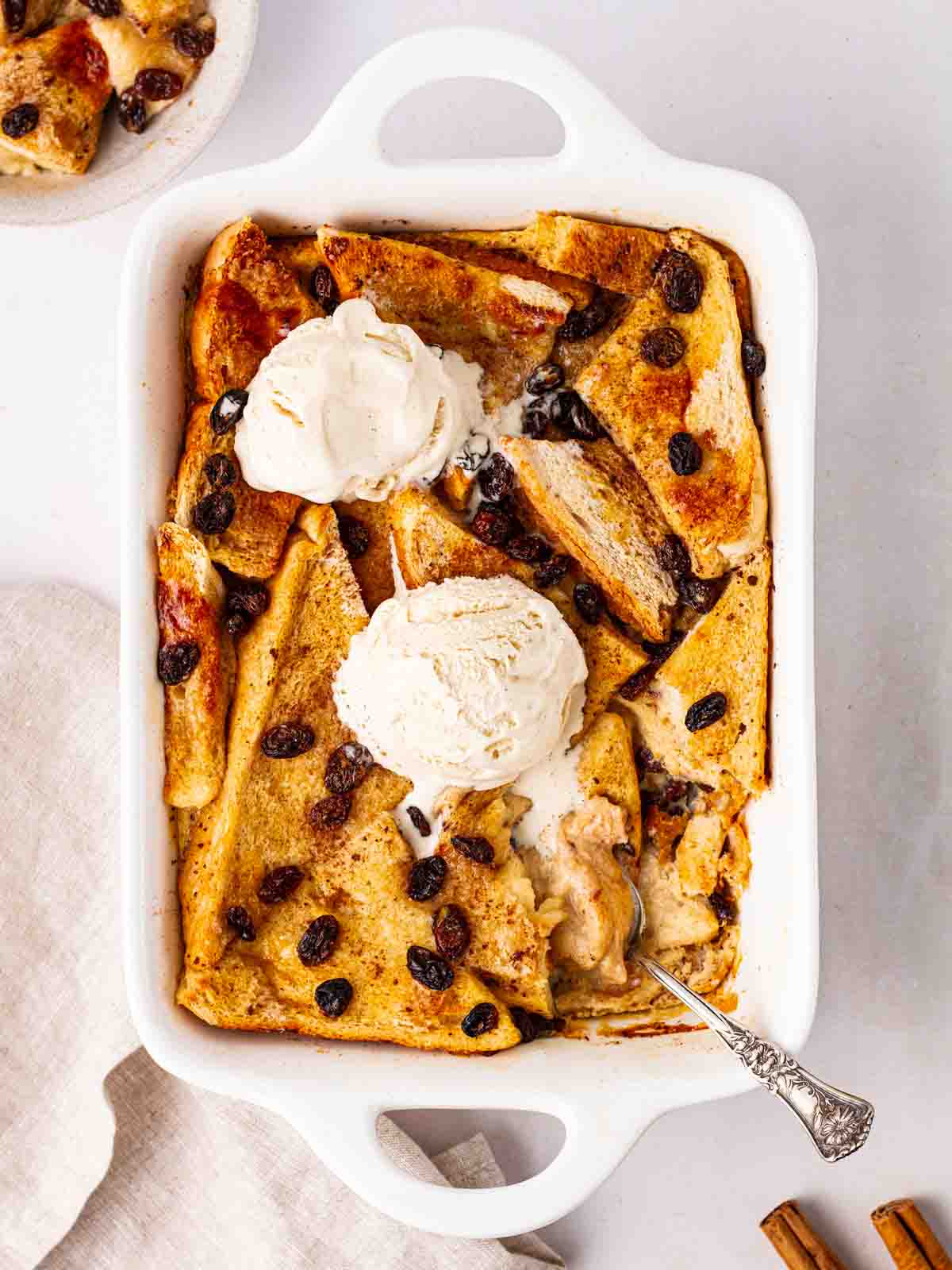 A white oven dish filled with classic bread and butter pudding, with ice cream on top.