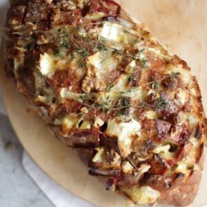 A baked loaf with brie and cranberry filling, and thyme on top, for a very festive bread for pulling apart and sharing.