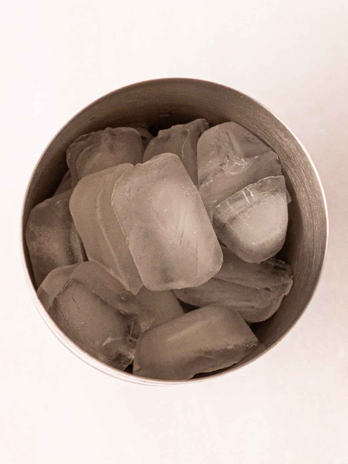 A cocktail mixer from the top with ice inside for step 1 in the recipe for Gin Fizz.