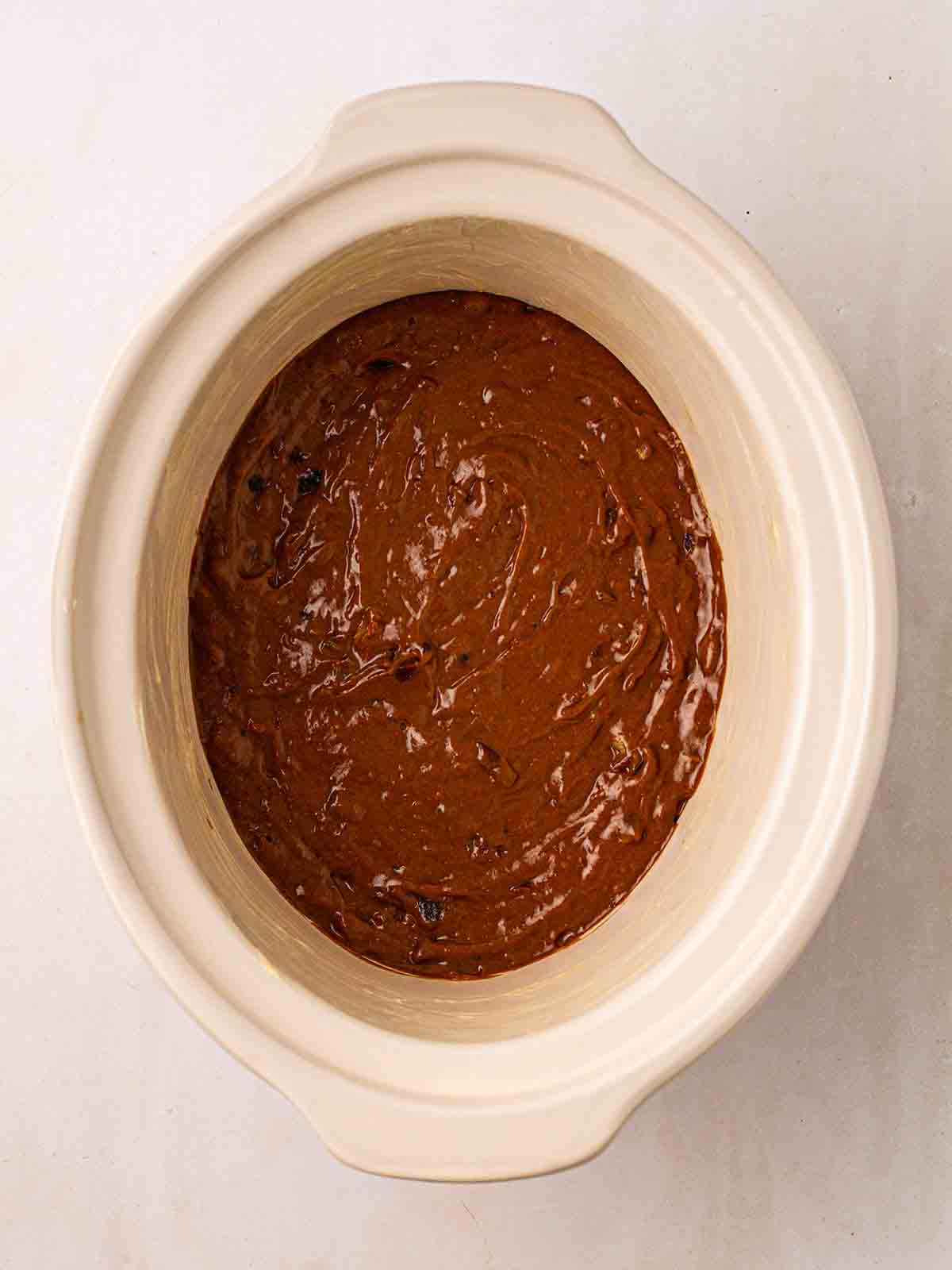 A slow cooker filled with mixture ready to make Sticky Toffee Pudding.