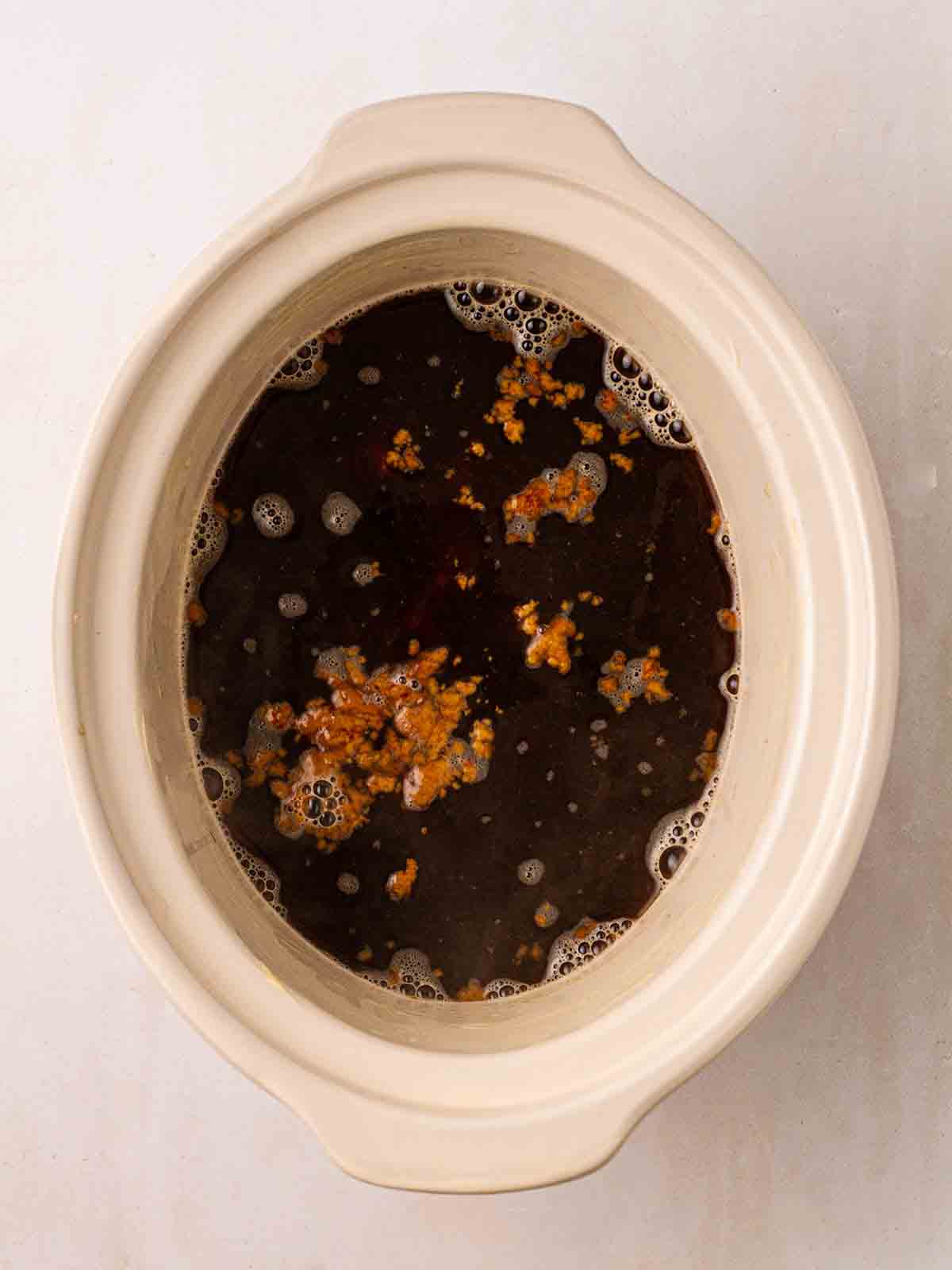 A slow cooker filled with sponge mixture and hot water for step 4 in the process for Sticky Toffee Pudding.