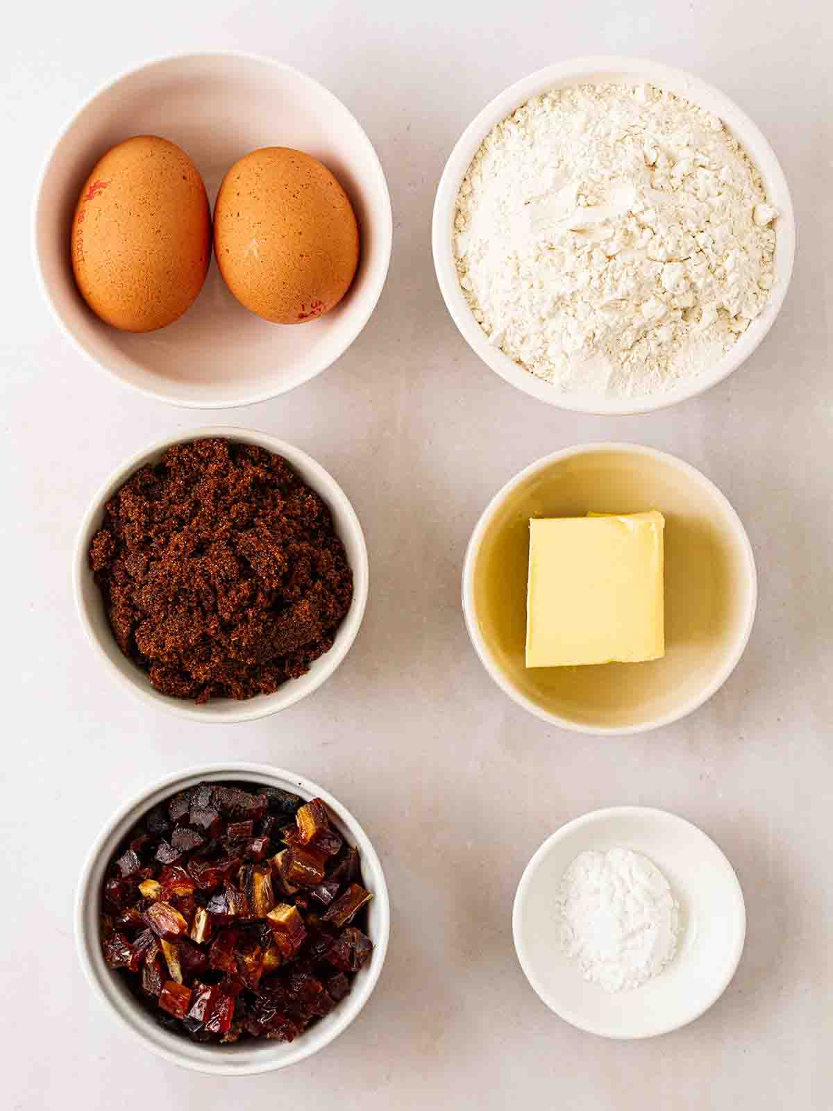 The ingredients to make slow cooker sticky toffee pudding laid out on a white counter.