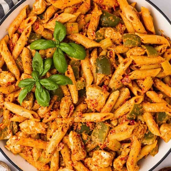 A bowl of one pan Cajun Chicken Pasta, ready to serve, with basil on top.