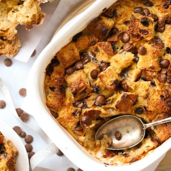 A baking dish filled with baked panettone bread and butter pudding, with a spoon ready to serve.