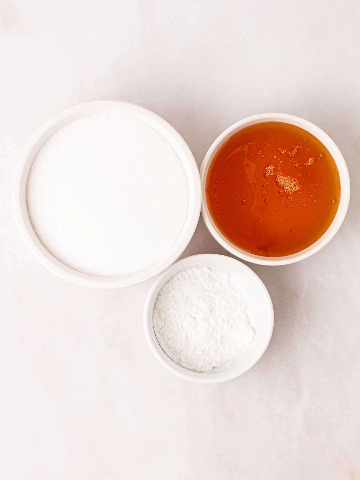 The ingredients for making honeycomb in three white bowls.