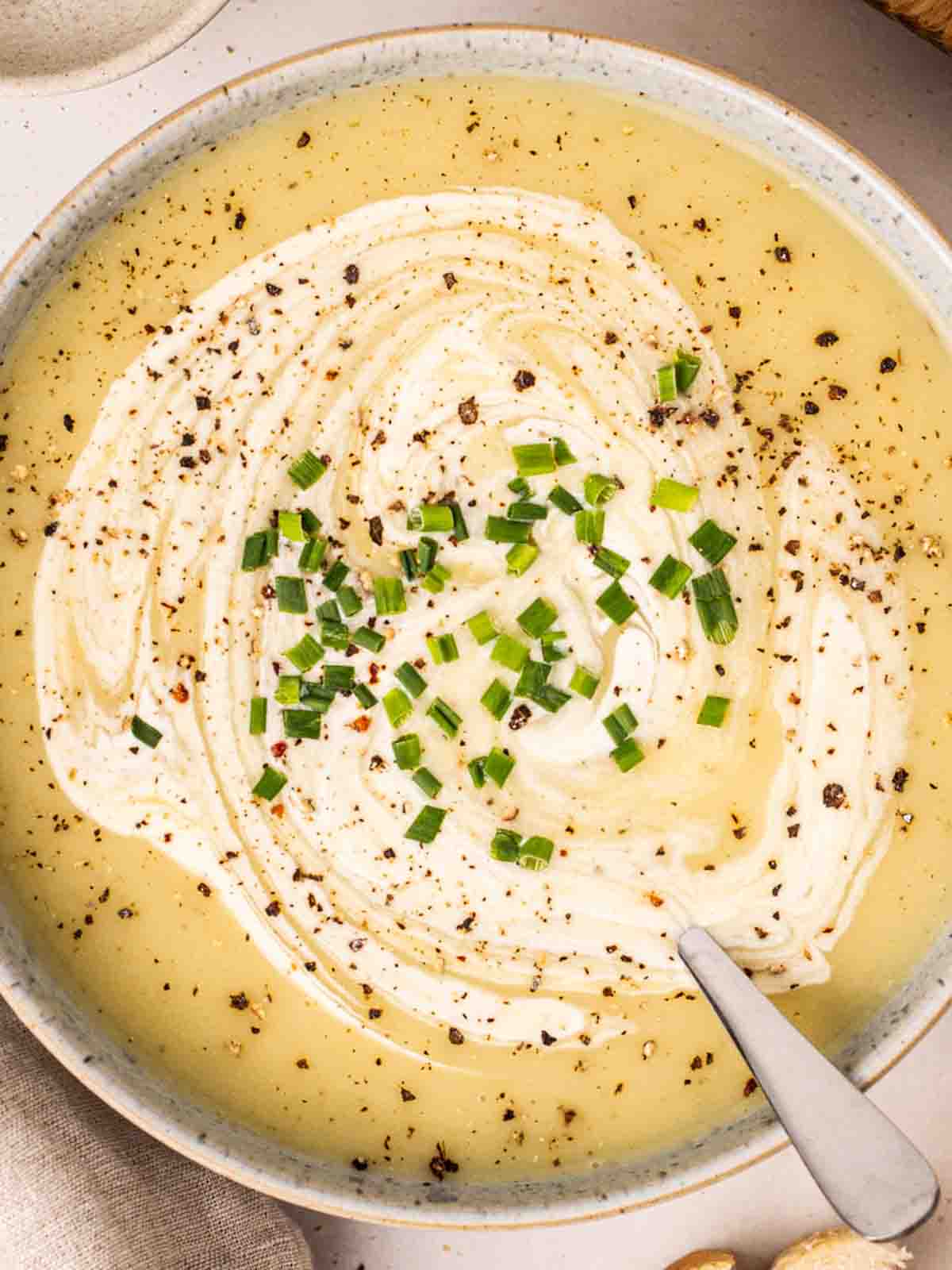 A bowl of leek and potato soup with a spoon.