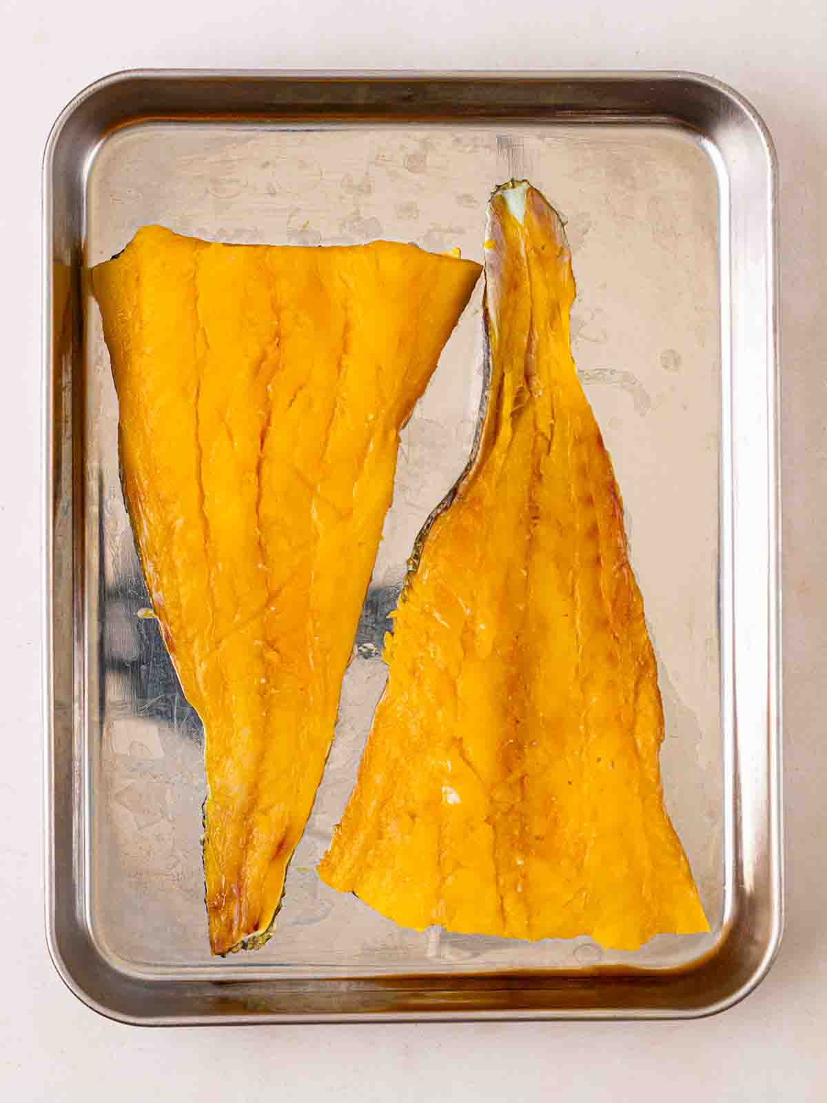 Two pieces of smoked haddock on a baking tray, ready to go in the oven for step 3 in the recipe for Smoked Haddock Risotto.