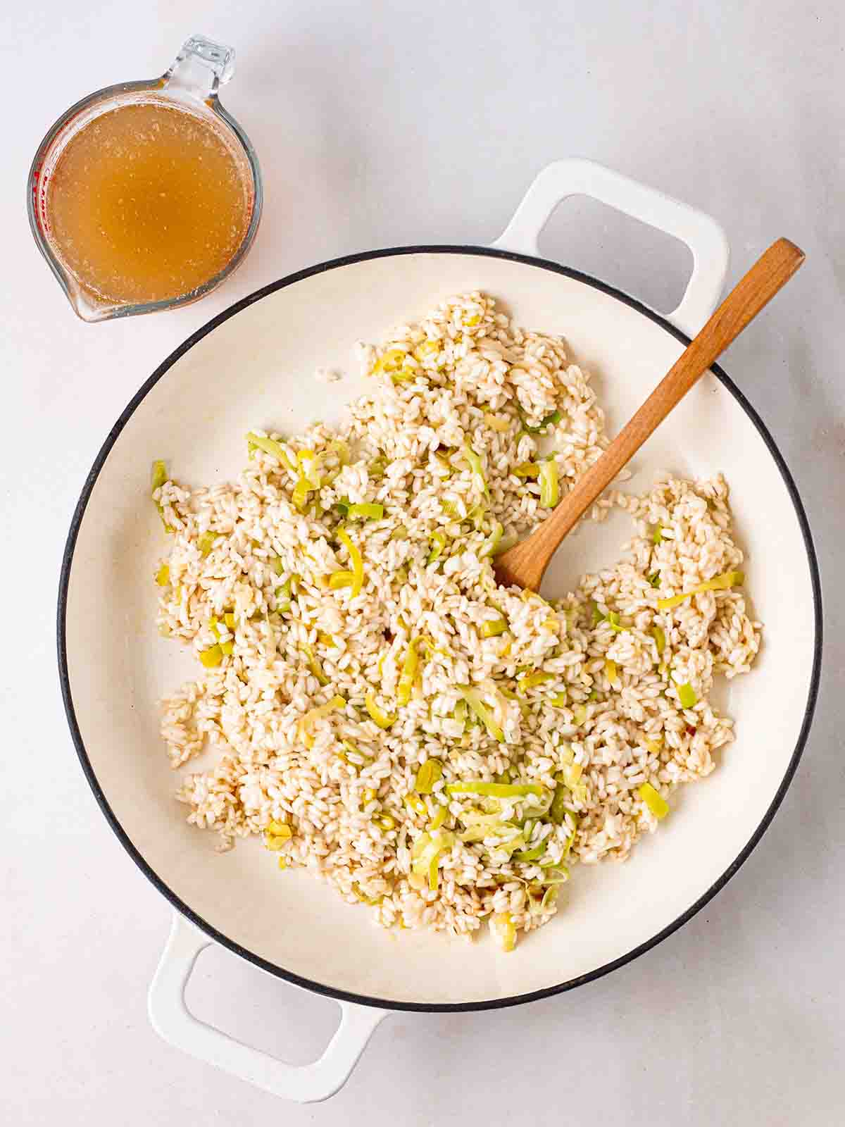 A pan filled with Smoked Haddock Risotto rice with stock to the side, ready to go in for step 4 in the recipe.