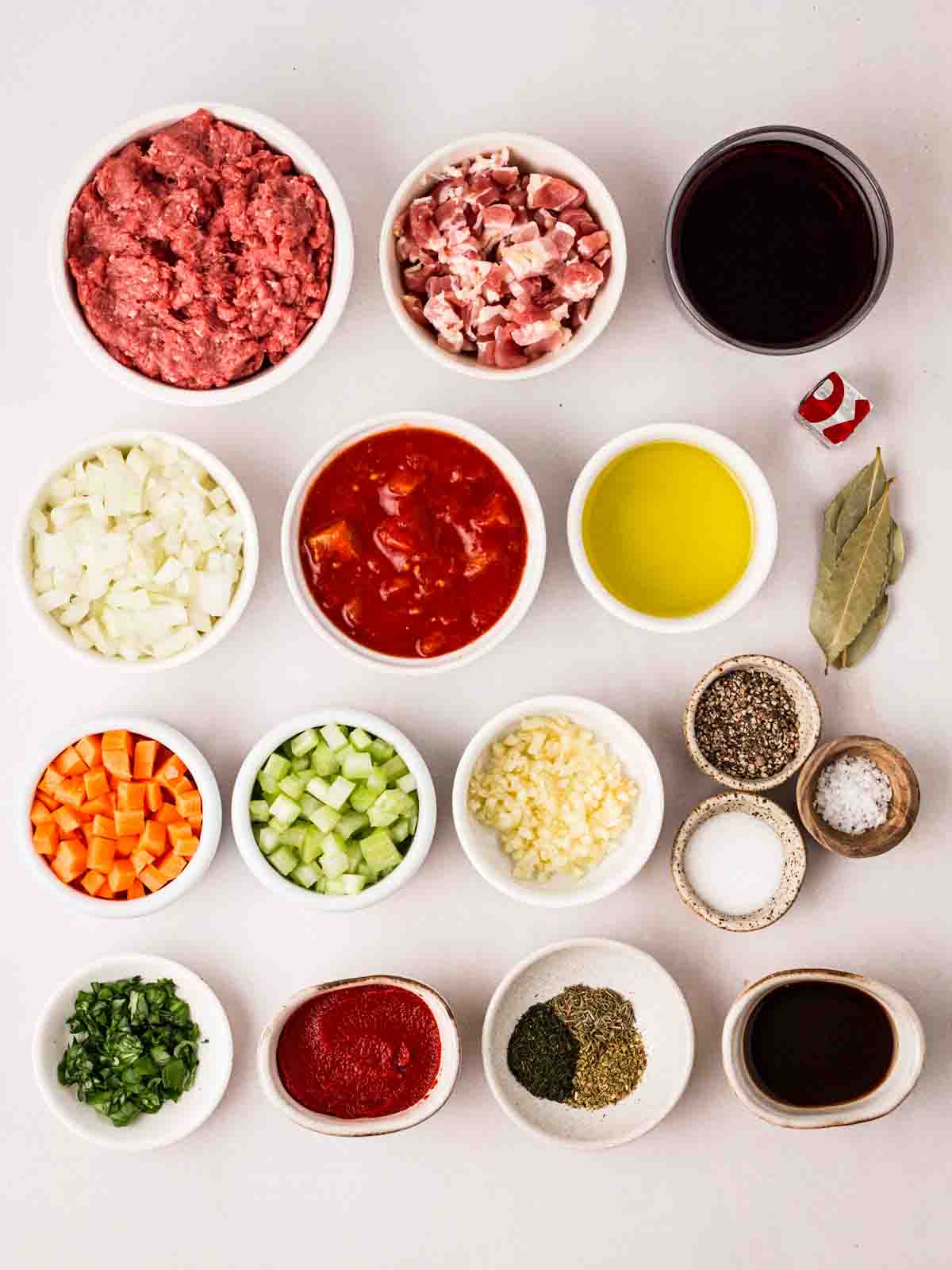The ingredients for spaghetti bolognese laid out on a table in small bowls.