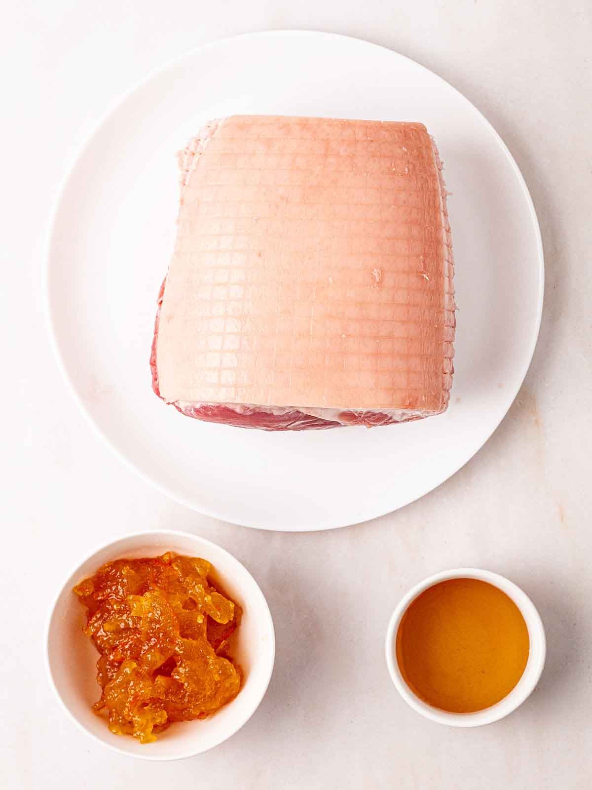 The ingredients for making a gammon joint in an air fryer laid out on a white counter. Gammon, marmalade and honey.
