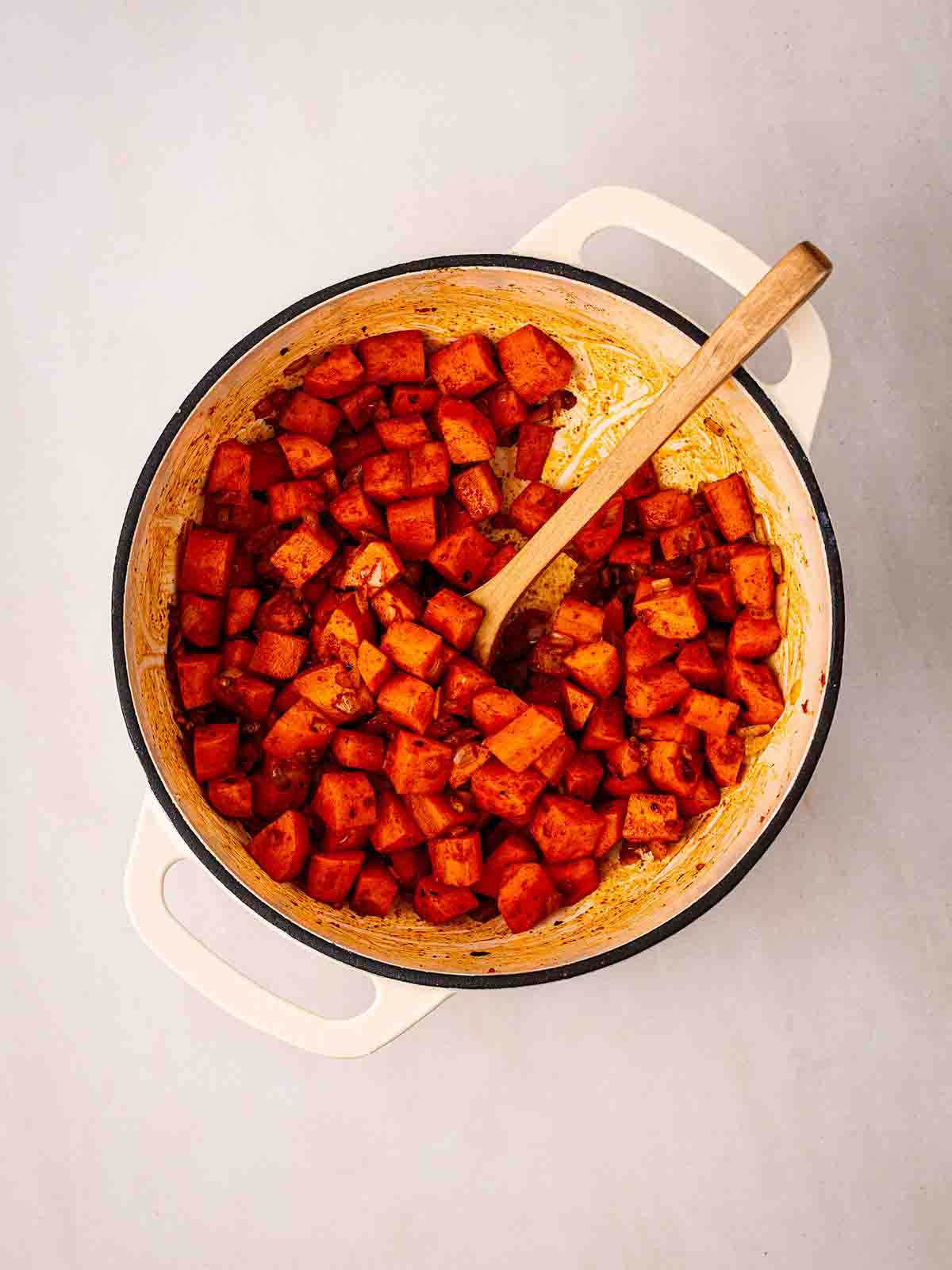 A white pan filled with cubes of carrots, covered in spices, for the recipe Carrot and Lentil Soup.