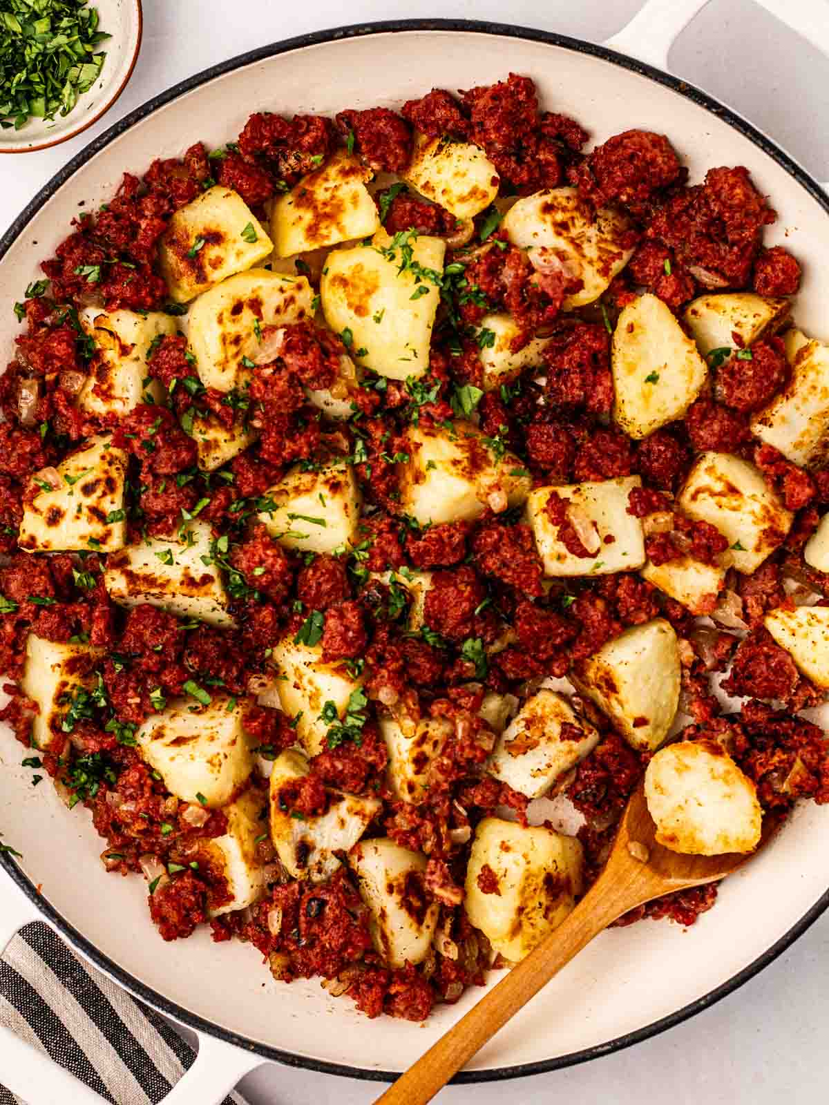 A plate of Corned Beef Hash, with a wooden spoon in.