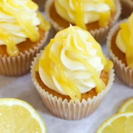 Lemon Cupcakes on a table with lemon frosting and lemon curd drizzled over the top.