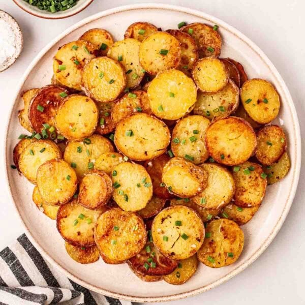 A bowl filled with crispy Sautéed Potatoes, garnished with chives, ready to eat.