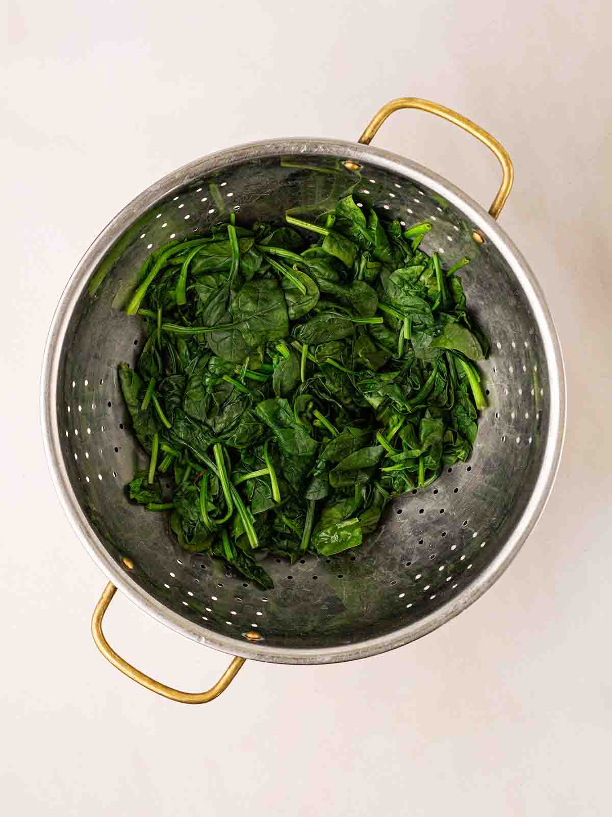 A colander filled with wilted spinach.