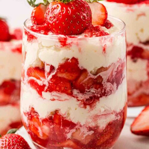 An individual portion of Eton Mess dessert, with layers of strawberries, cream and meringue.