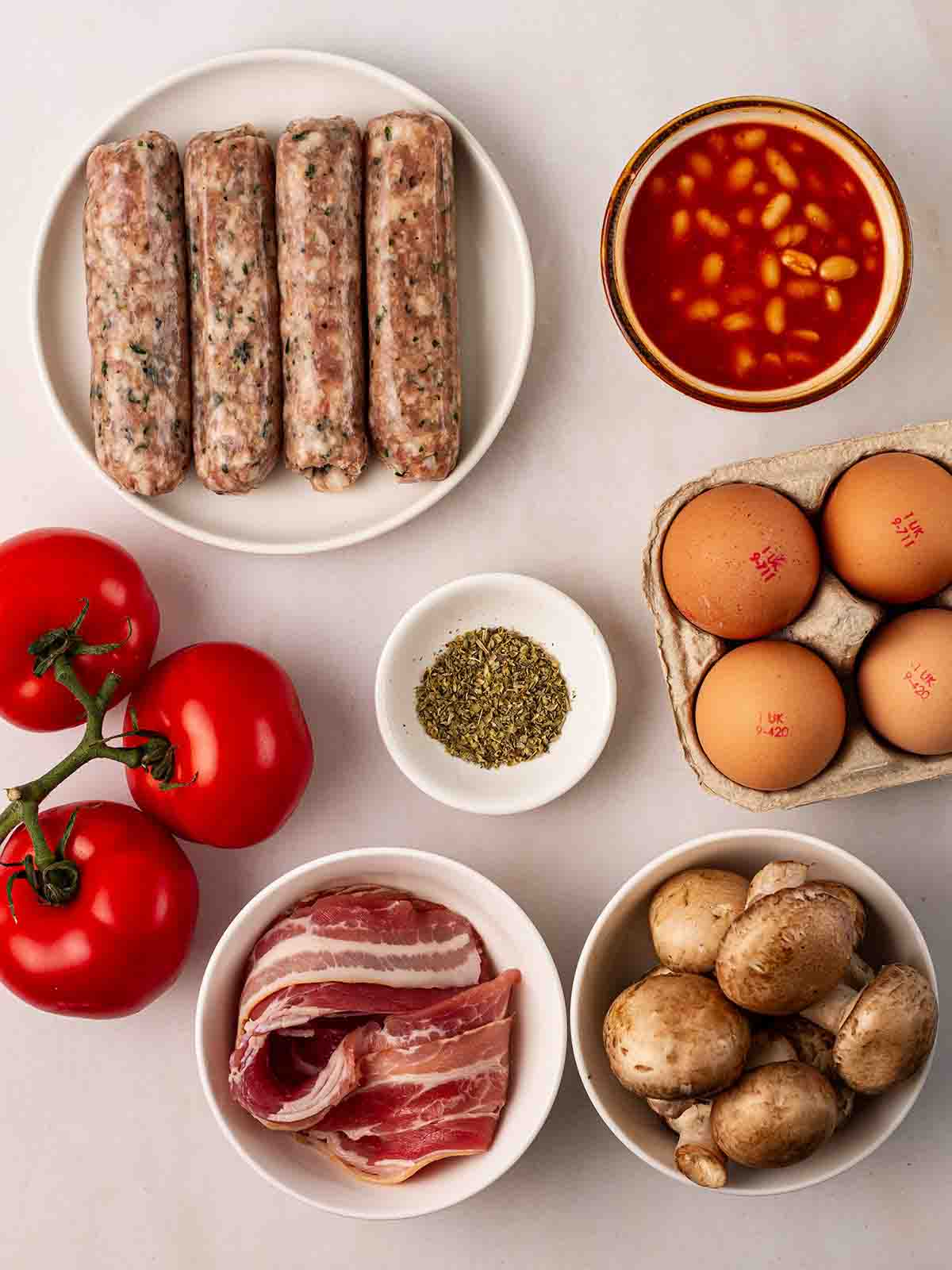 The ingredients for making a Full English Breakfast laid out in bowls on a counter top.