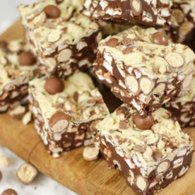 A chopping board with squares of Maltesers Rocky Road on stop of each other.