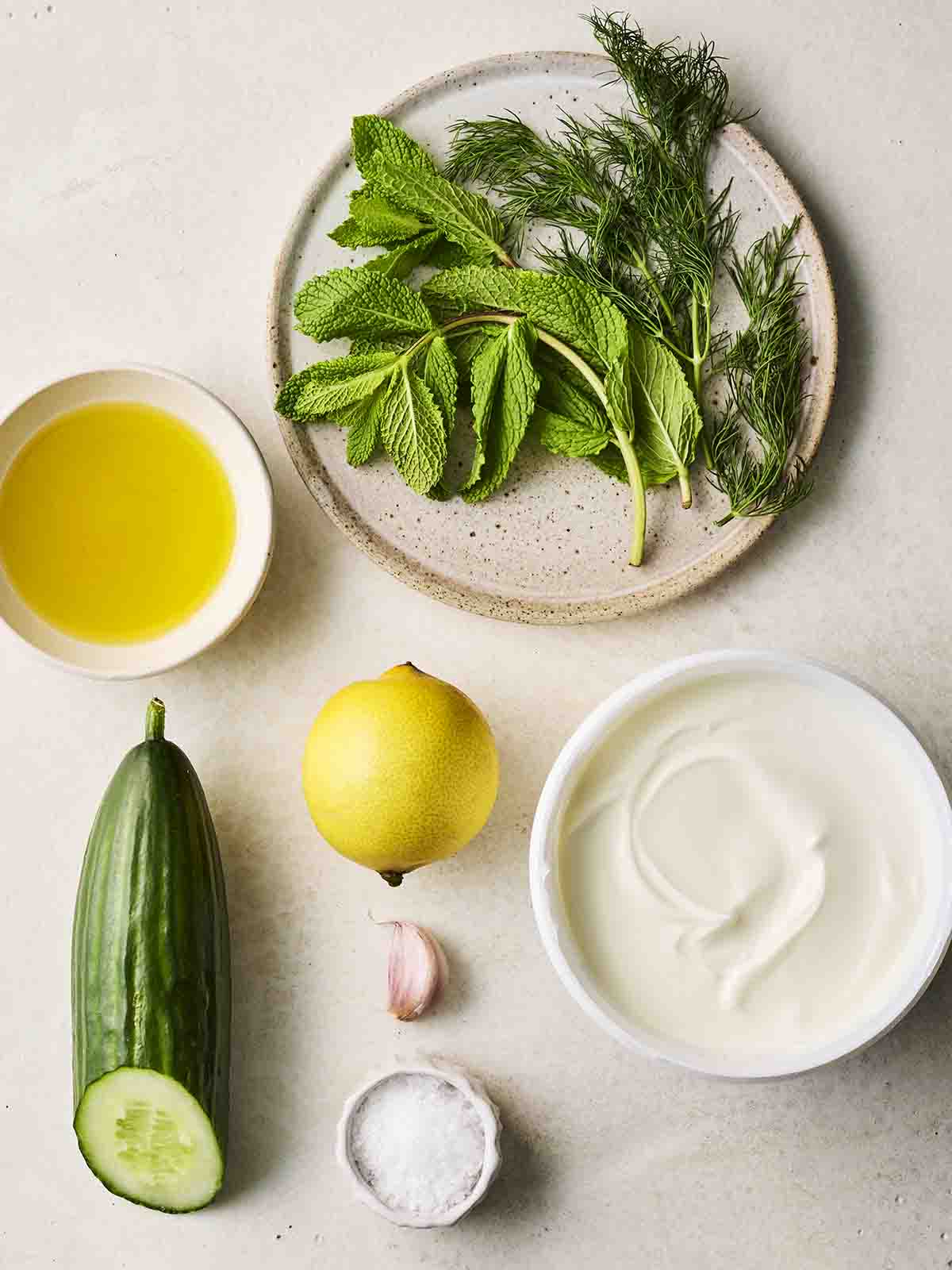 The ingredients for making Tzatziki laid out in bowls on a counter.