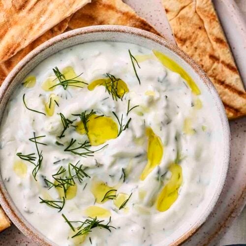 A bowl filled with homemade tzatziki and pittas to dip in.
