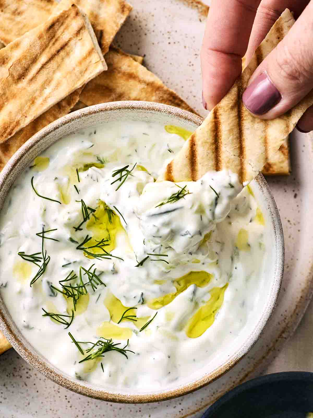 Tzatziki dip in a bowl with a pitta being dipped.