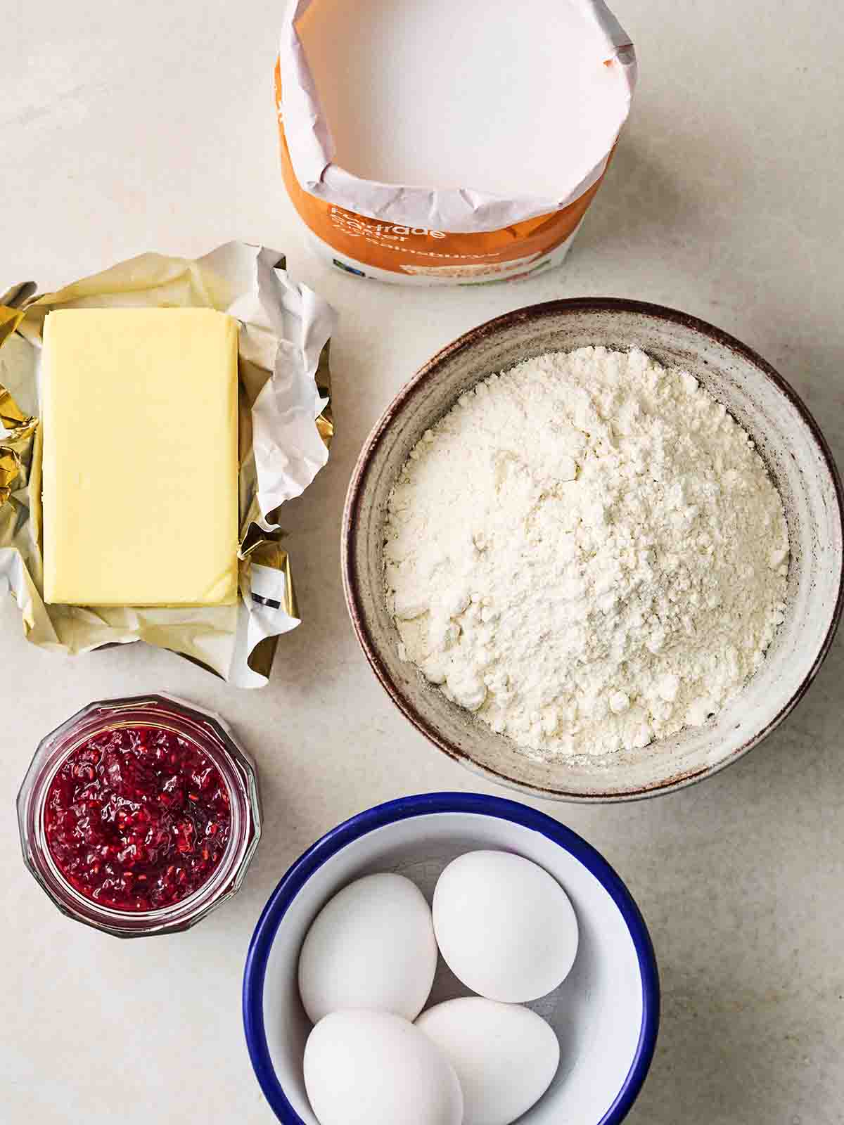 The ingredients for making a Victoria Sponge cake laid out on a counter top.