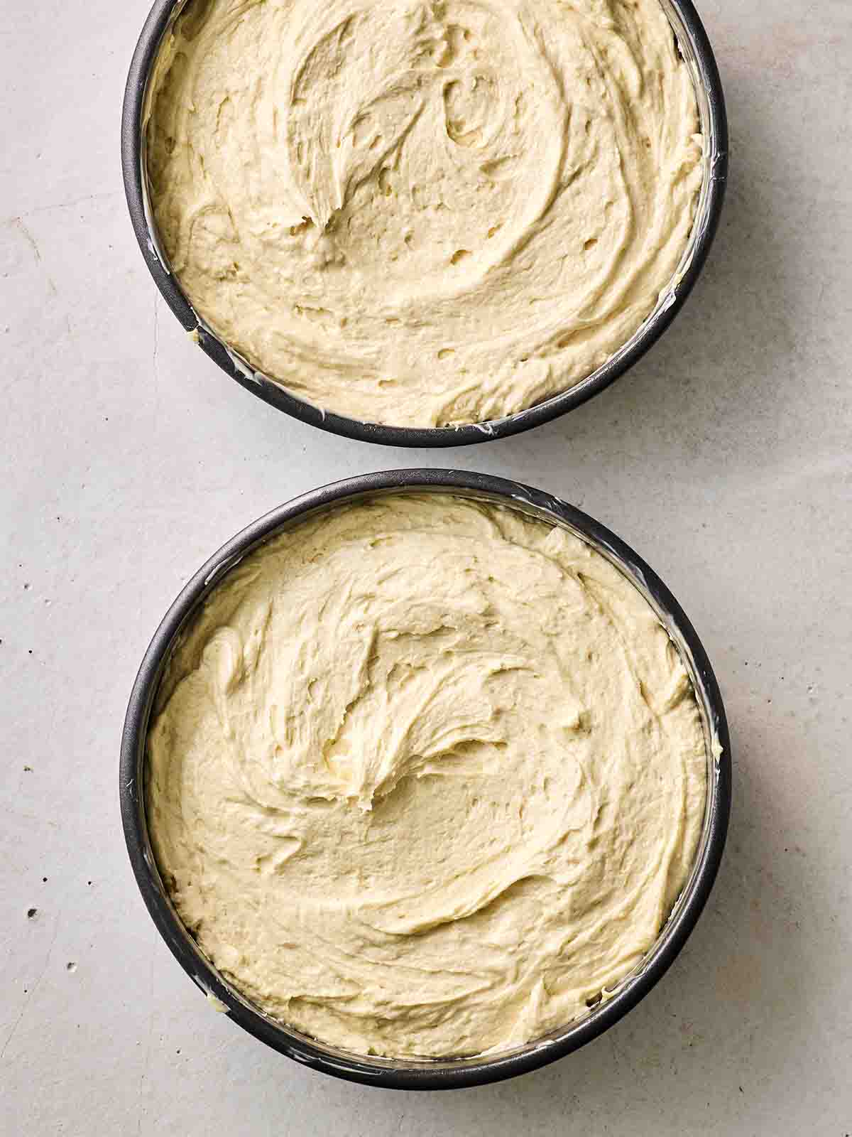 Two cake tins filled with sponge batter, ready to go in the oven to make Victoria Sponge Cake.