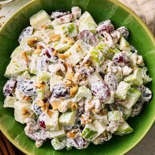A green bowl with a Classic Waldorf Salad, with grapes, apple, walnuts, celery and a mayo, yoghurt dressing.