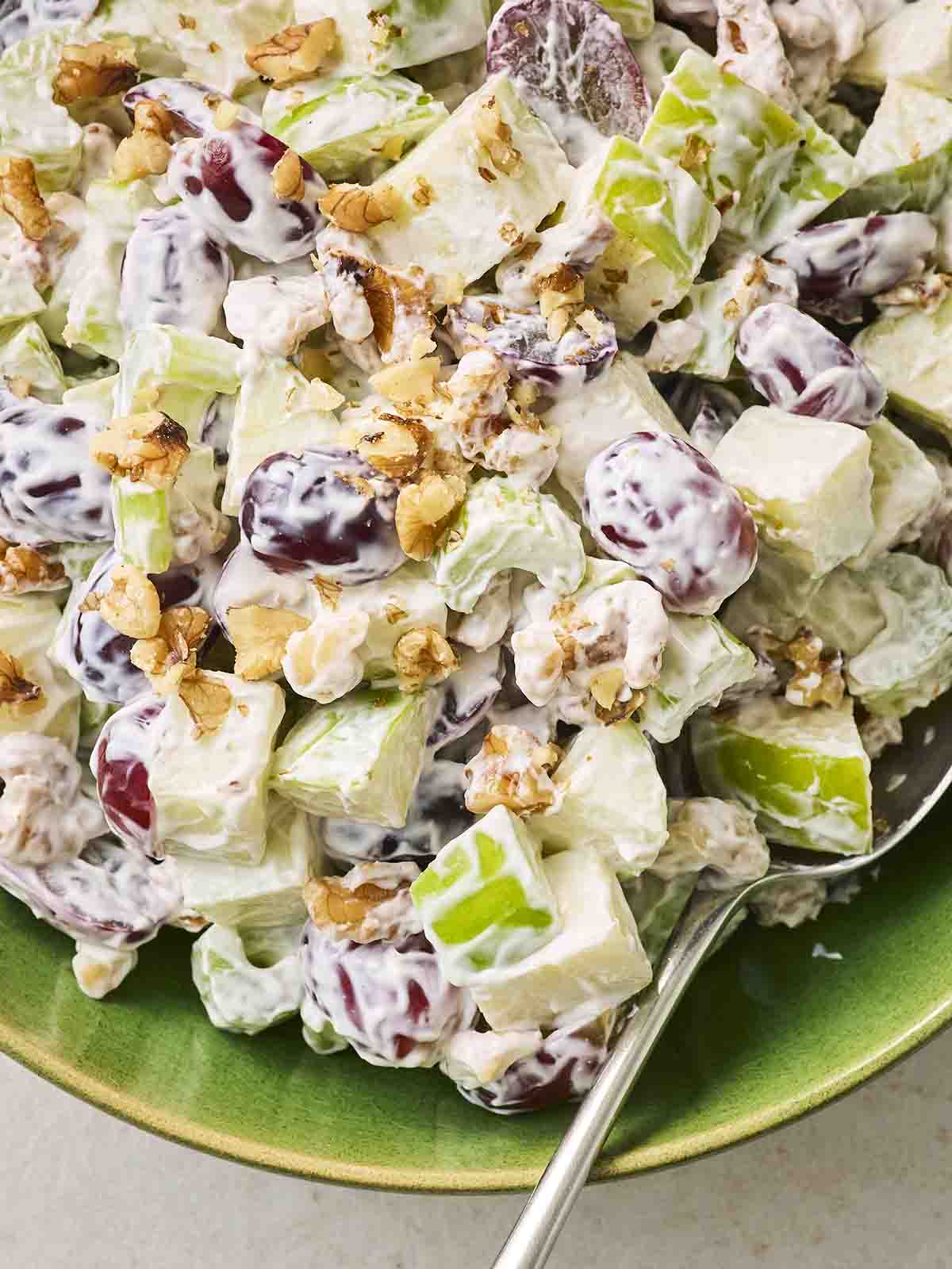 A chopped Walford Salad in a green bowl, with a spoon ready to serve.