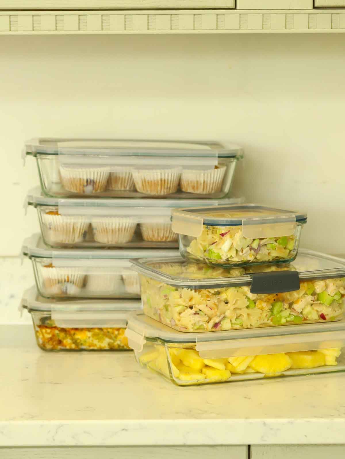 Glass meal prep containers on a counter, filled with lots of made-ahead food for the week ahead.