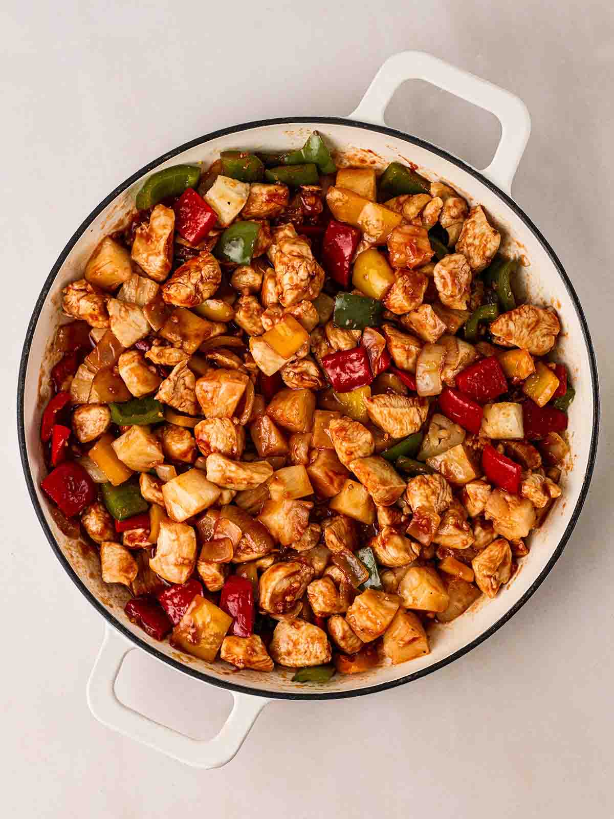 Chicken with peppers, pineapple in a pan for step 2 in Sweet and Sour Chicken.