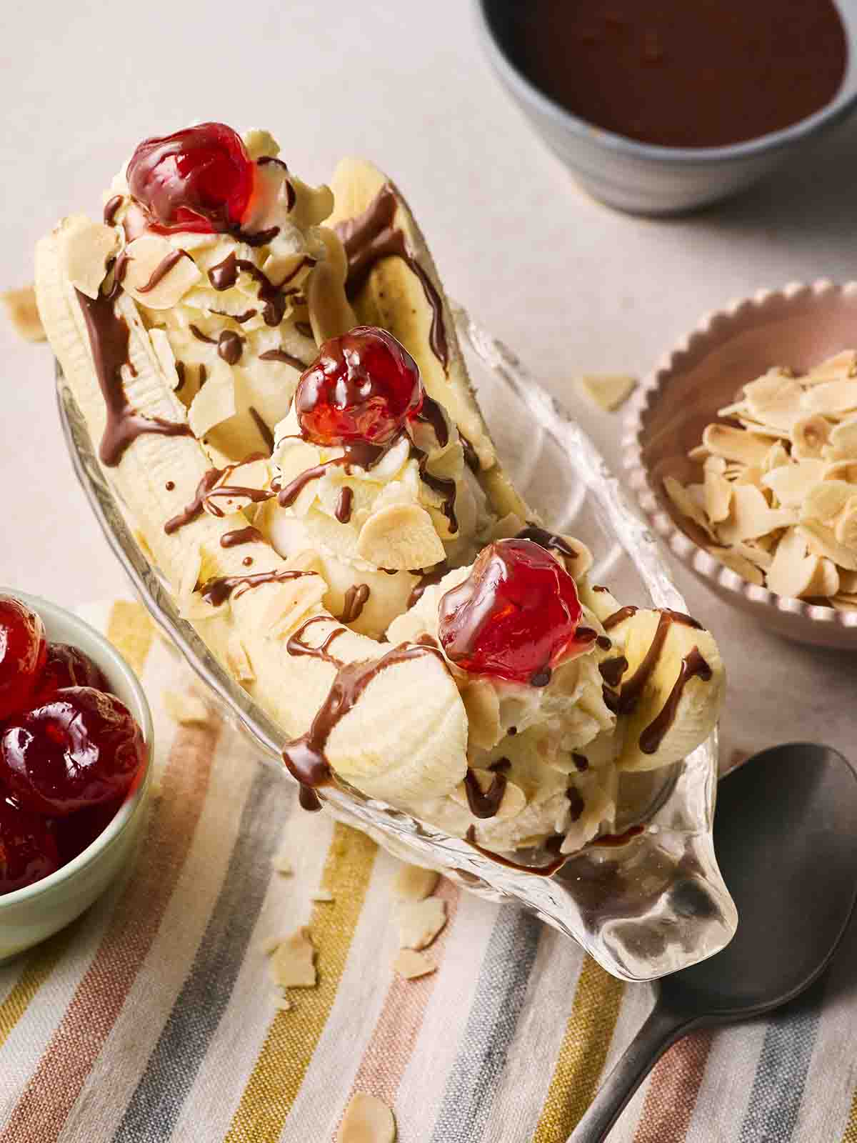 A classic Banana Split with cherries and chocolate sauce in a boat dish.