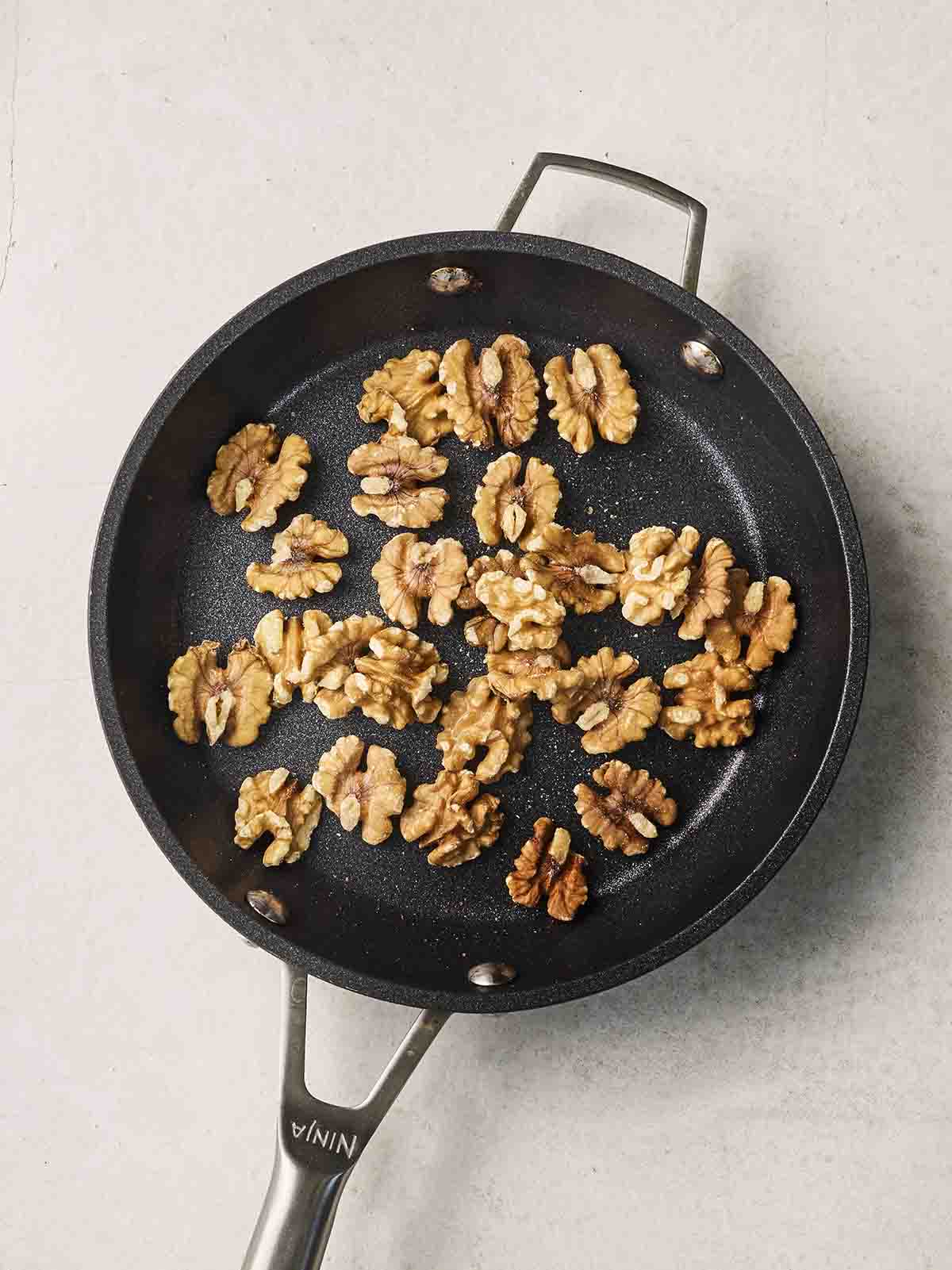 Walnuts toasting in a pan.
