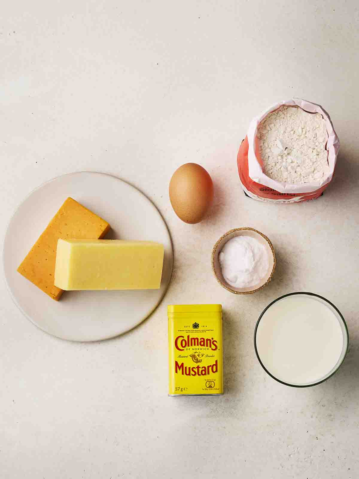The ingredients for making Cheese Scones laid out on a white surface from above.