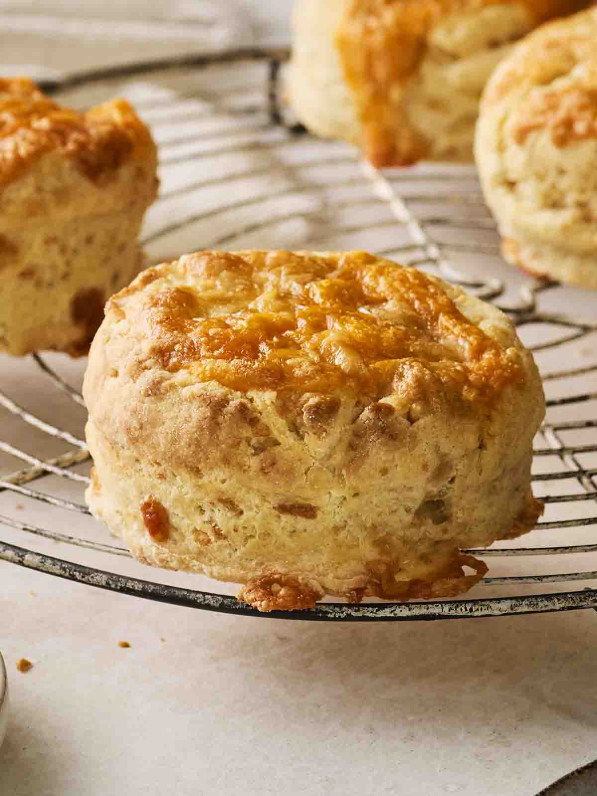 A cheese scone on a wire rack, looking from the side.