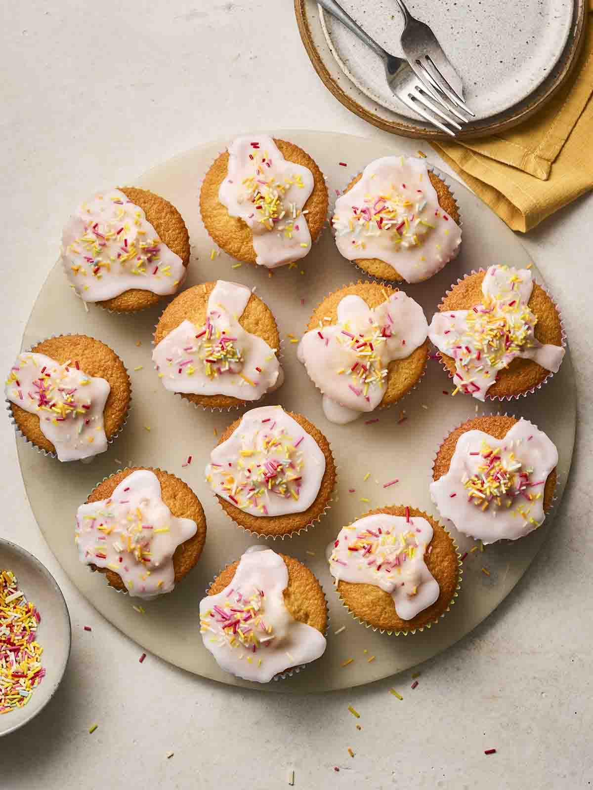 A plate of iced fairy cakes, ready to eat.