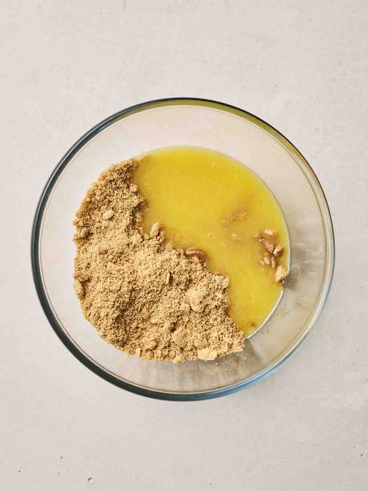 Melted butter and crushed digestives in a glass bowl.