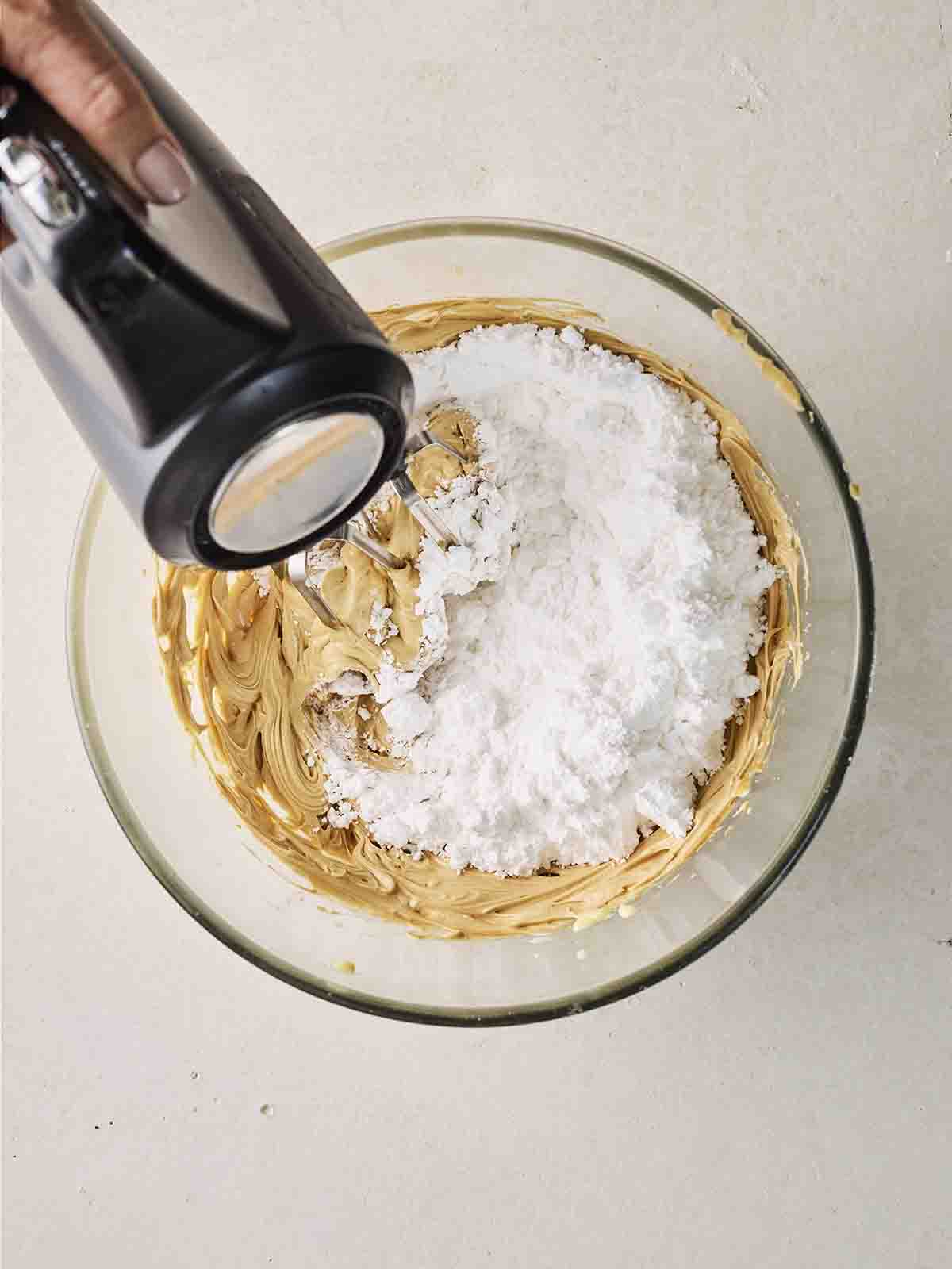 Biscoff buttercream with icing being whisked in with an electric whisk.