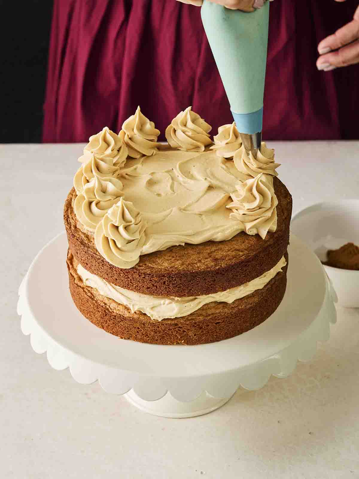 Biscoff Buttercream being piped on top of the cake.