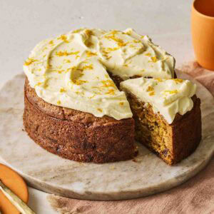 A slice of carrot cake being pulled from the rest of the cake, ready to eat.