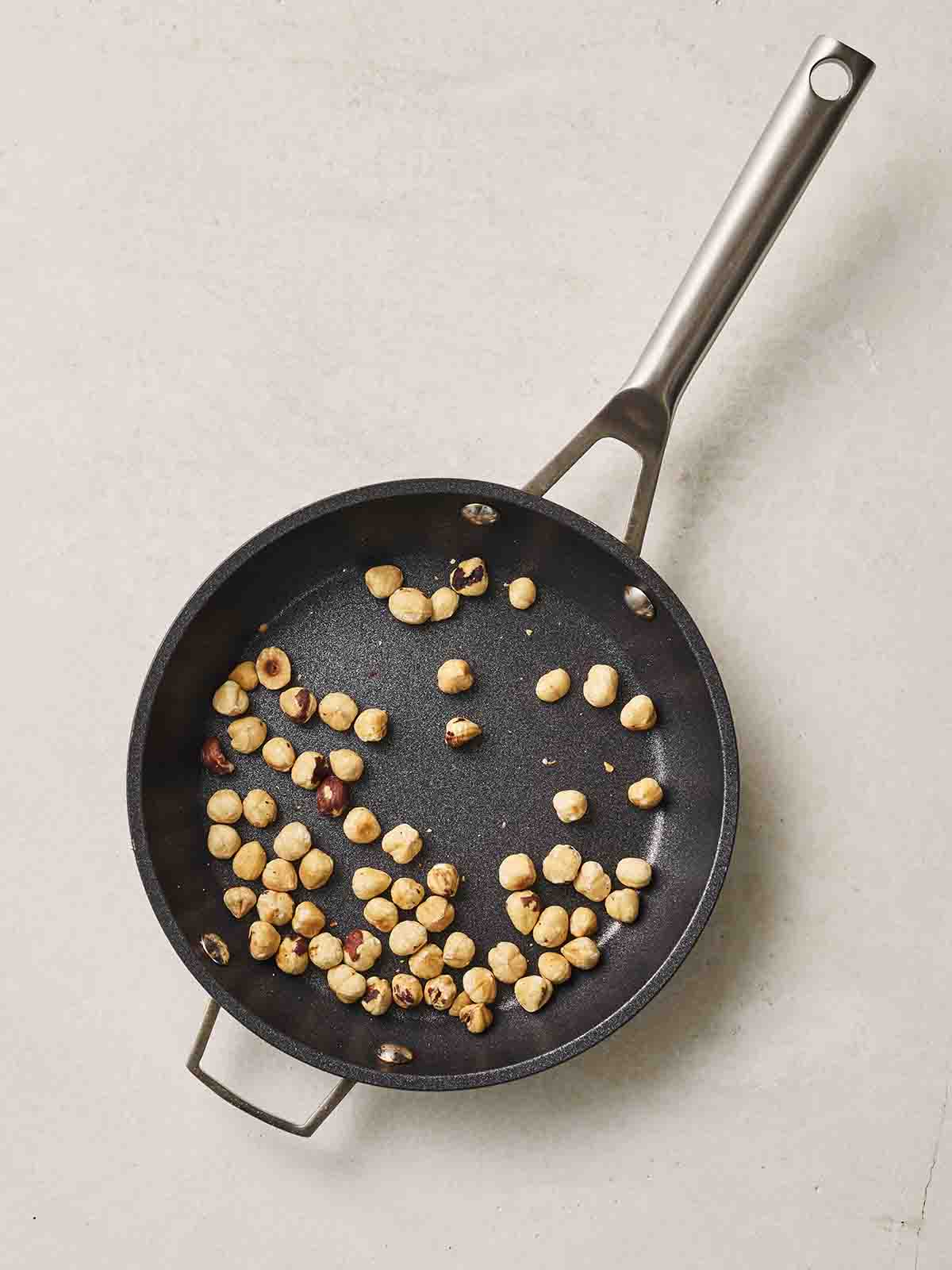 Hazelnuts toasting in a pan.