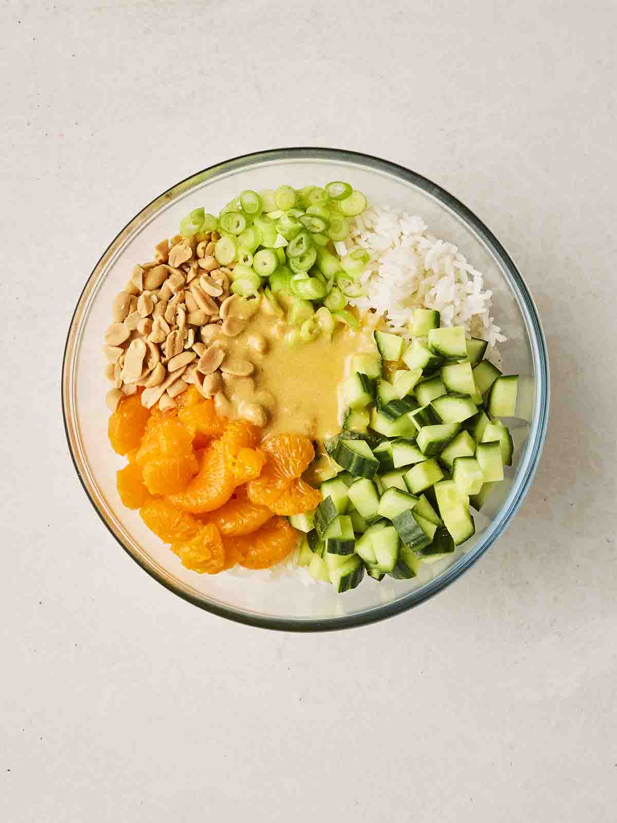 The ingredients for making a rice salad in bowl together, ready to be mixed with the dressing that's on top.
