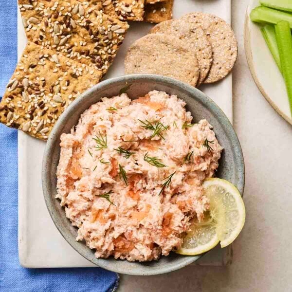 A bowl of homemade Salmon Pate on in a bowl, on a plate with crackers and celery to the side.