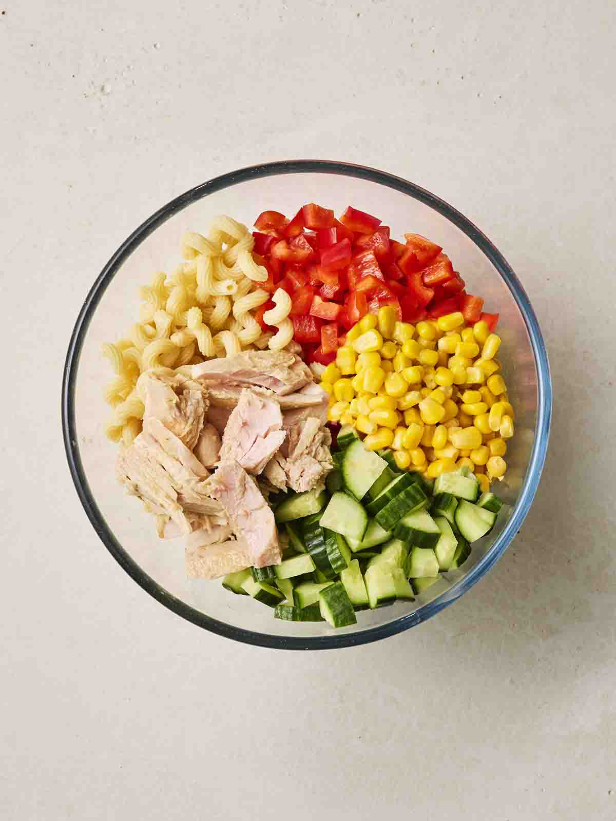 The ingredients for Tuna Pasta Salad mixed together in a bowl for step 1 in the recipe.